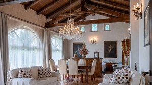 A spacious living room with a high wooden ceiling, a chandelier, and a dining area with a wooden table and chairs. - Villa Carlotta by Interhome (Costigliole d'Asti)