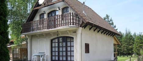 Un edificio de dos plantas con balcón, una ventana grande y un pequeño porche.