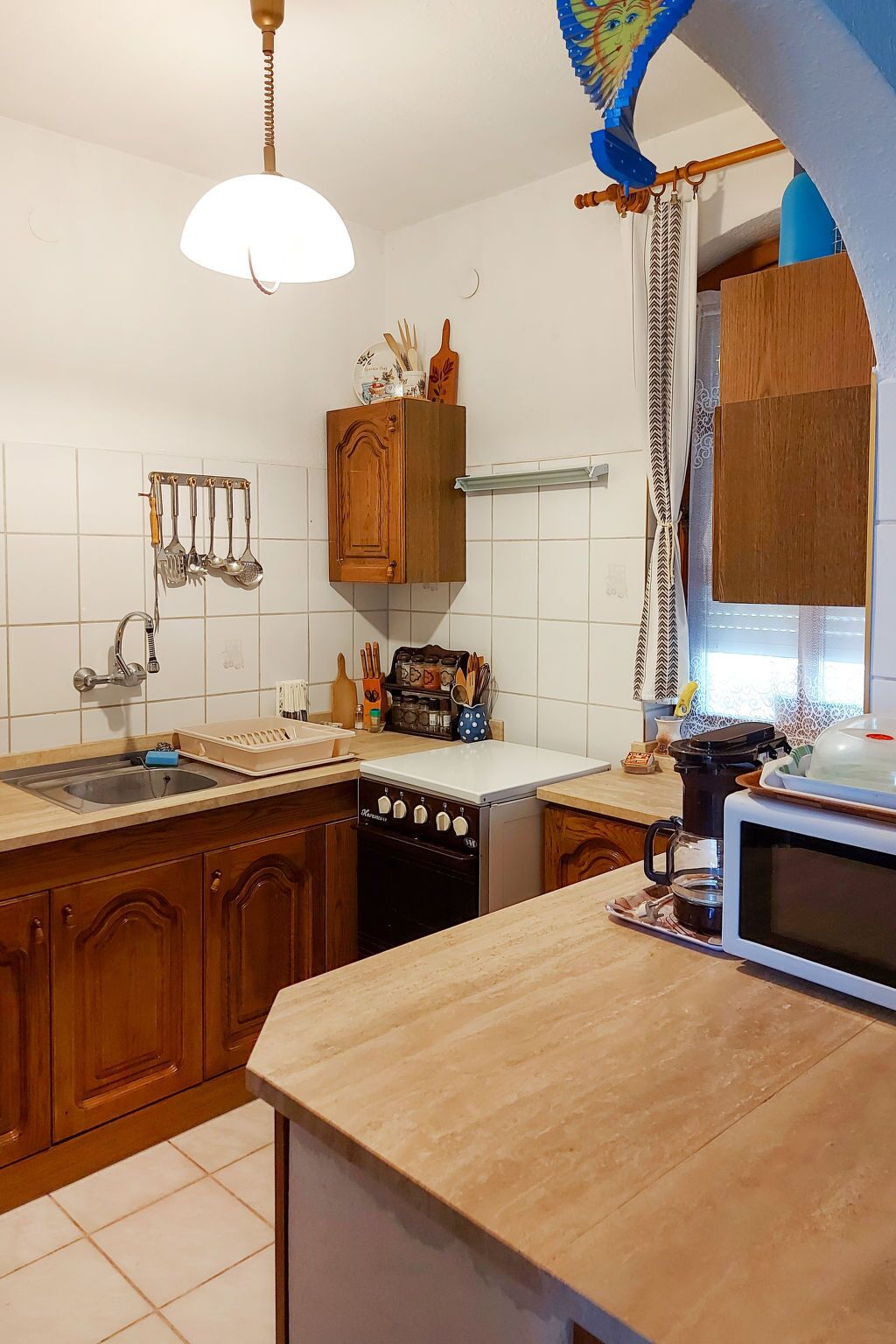 Una cocina con armarios de madera, horno empotrado, microondas y pileta.