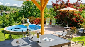 Une terrasse avec une piscine, des sièges d’extérieur et une pergola.