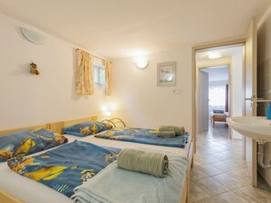 Una habitación de hotel con dos camas, un baño con lavamanos y una puerta que da a otra habitación.