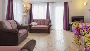 A living room with a sofa, armchair, and a table with colorful tablecloths. - Annemarie by Interhome (Balatonalmadi)