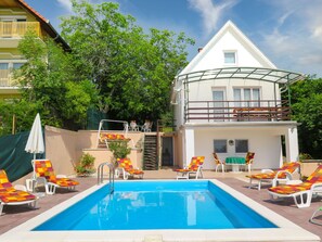 Una piscina con sillas de descanso y un edificio con balcón.