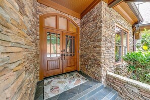 A stone exterior with a wooden double door and a tiled entryway.