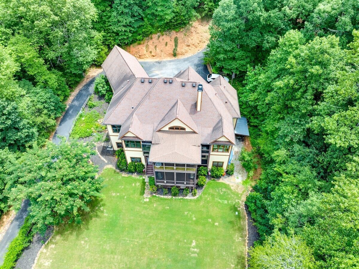 A large house with a spacious lawn, a driveway, and a river nearby.