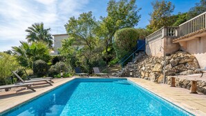 A rectangular swimming pool with clear blue water, surrounded by lounge chairs and a stone wall with a staircase. - Bartavelle by Interhome (Sainte Maxime)