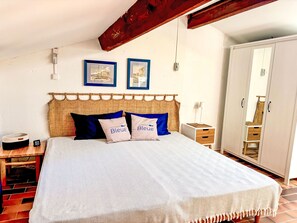 Une chambre à coucher comprenant un lit, une table de chevet, une armoire et deux tableaux encadrés accrochés au mur.