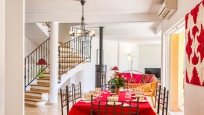 A dining area with a red tablecloth, a chandelier, and a staircase leading to an upper floor. - Villa Faro by Interhome (Montfort)