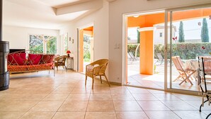 A spacious living area with a sofa, chairs, and a dining table. There is a sliding glass door leading to an outdoor patio area. - Villa Faro by Interhome (Montfort)