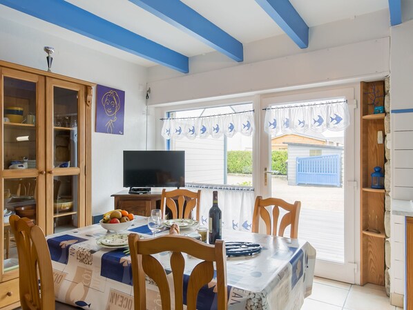 A dining area with a table set for four, a television, and a view of the outside.