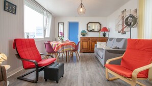 A living room with a dining area, a sofa, and a chair with a red cushion. - Ti an Aod by Interhome (Cléder)