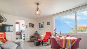 A modern living room with a sofa, chairs, a dining table with chairs, a TV, and a kitchen area. - Ti an Aod by Interhome (Cléder)
