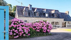 A stone building with a traditional architectural style, featuring a steeply pitched roof and multiple chimneys. - Ker Iliav by Interhome (Plouescat)