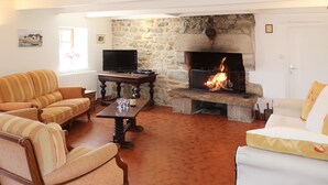 A living room with a stone fireplace, a television, and two sofas. - Ker Iliav by Interhome (Plouescat)
