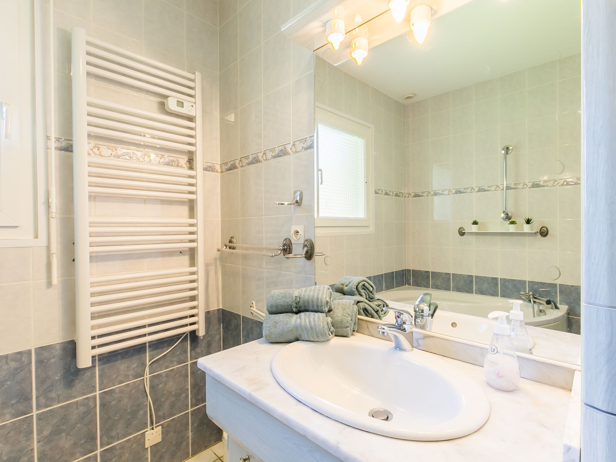Une salle de bain moderne avec un lavabo blanc, un miroir, un porte-serviettes et un espace douche.