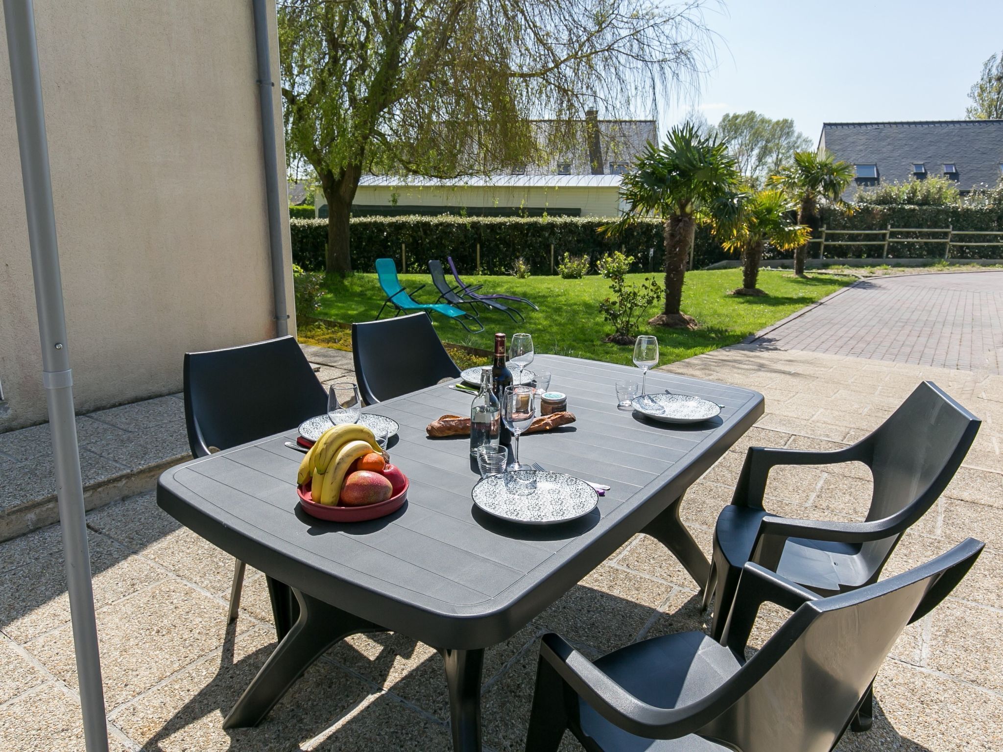 Un espacio de comedor al aire libre con una mesa dispuesta para dos personas, rodeado de sillas.