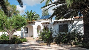Ein traditionelles Gebäude im mediterranen Stil mit Innenhof, Rundbogenöffnungen und einer gefliesten Terrasse.