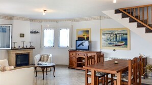 A spacious living room with a fireplace, a dining area, and a staircase. - Vacation home Silvia by Interhome (Miami Platja)