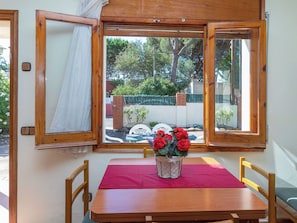 A wooden table with a red tablecloth, two chairs, and a potted plant with red flowers. - Bretos 7 by Interhome (Calonge)
