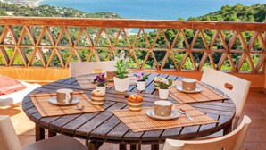 A round wooden table with placemats, cups, and small potted plants on a balcony overlooking a coastal landscape. - Xarmada Guillermo by Interhome (Begur)