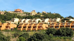 A hillside residential area with multiple two-story buildings, each featuring balconies and a uniform architectural style. - Xarmada Guillermo by Interhome (Begur)