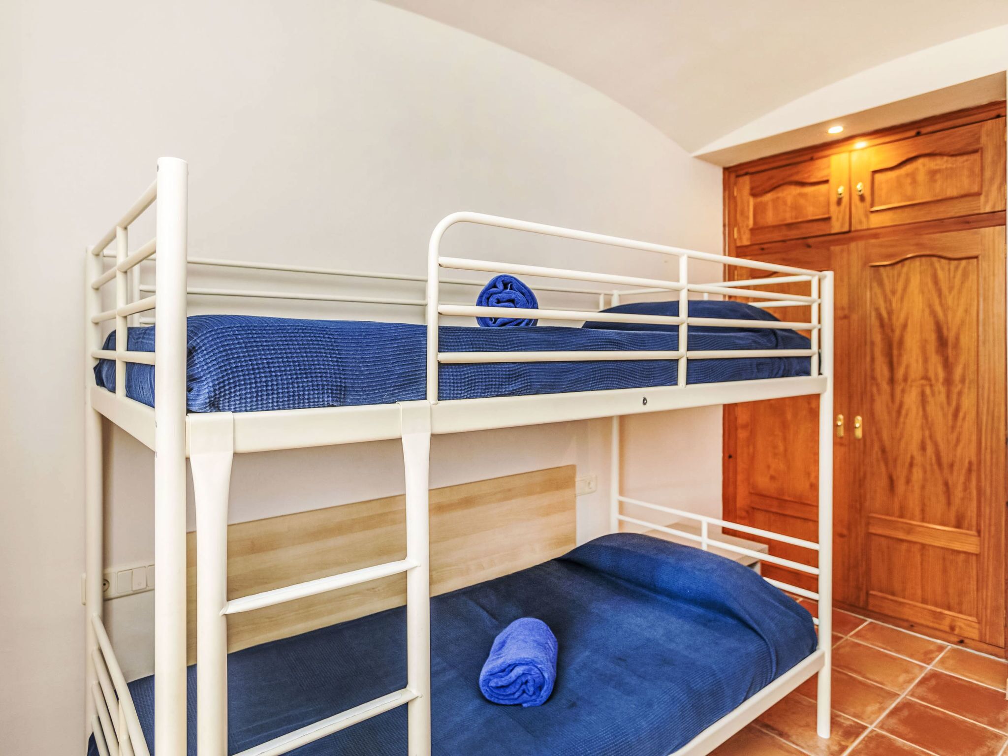A bunk bed with two levels, a wooden door, and a tiled floor.