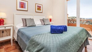 Une chambre à coucher avec un lit, deux tables de chevet, une fenêtre et un balcon.
