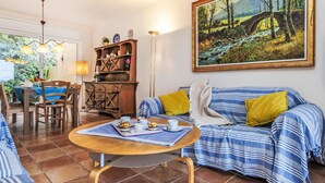 Un salon comprenant un canapé, une table à manger et un tableau représentant un paysage.