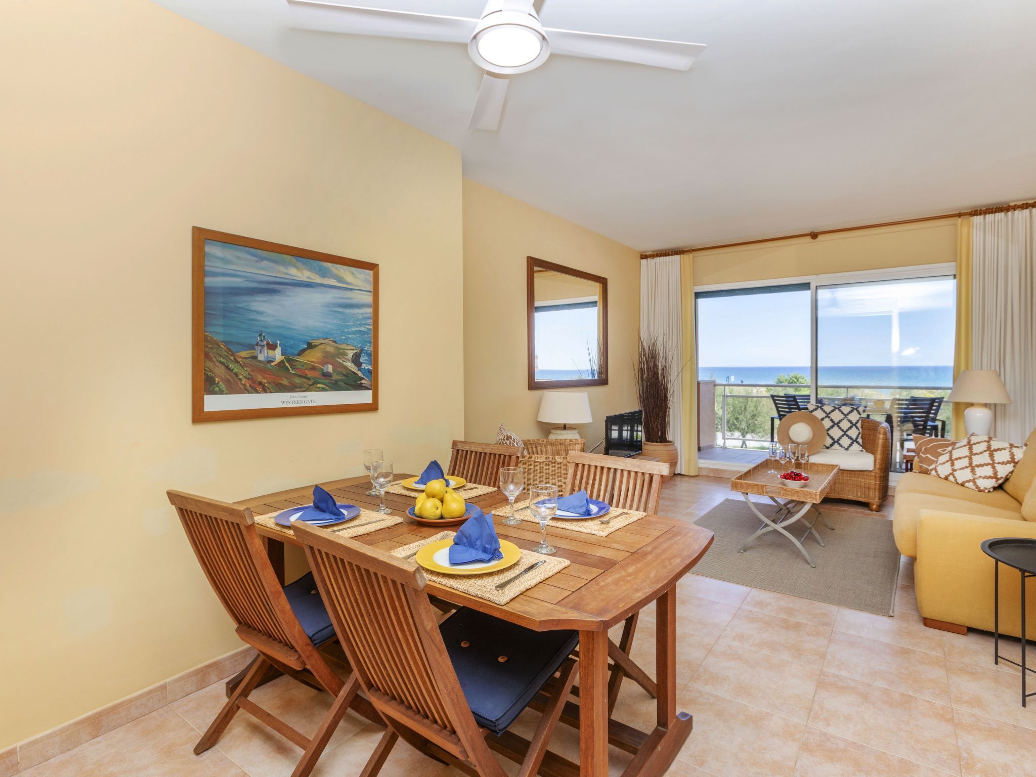 A dining area with a wooden table, chairs, and a painting of a coastal scene.