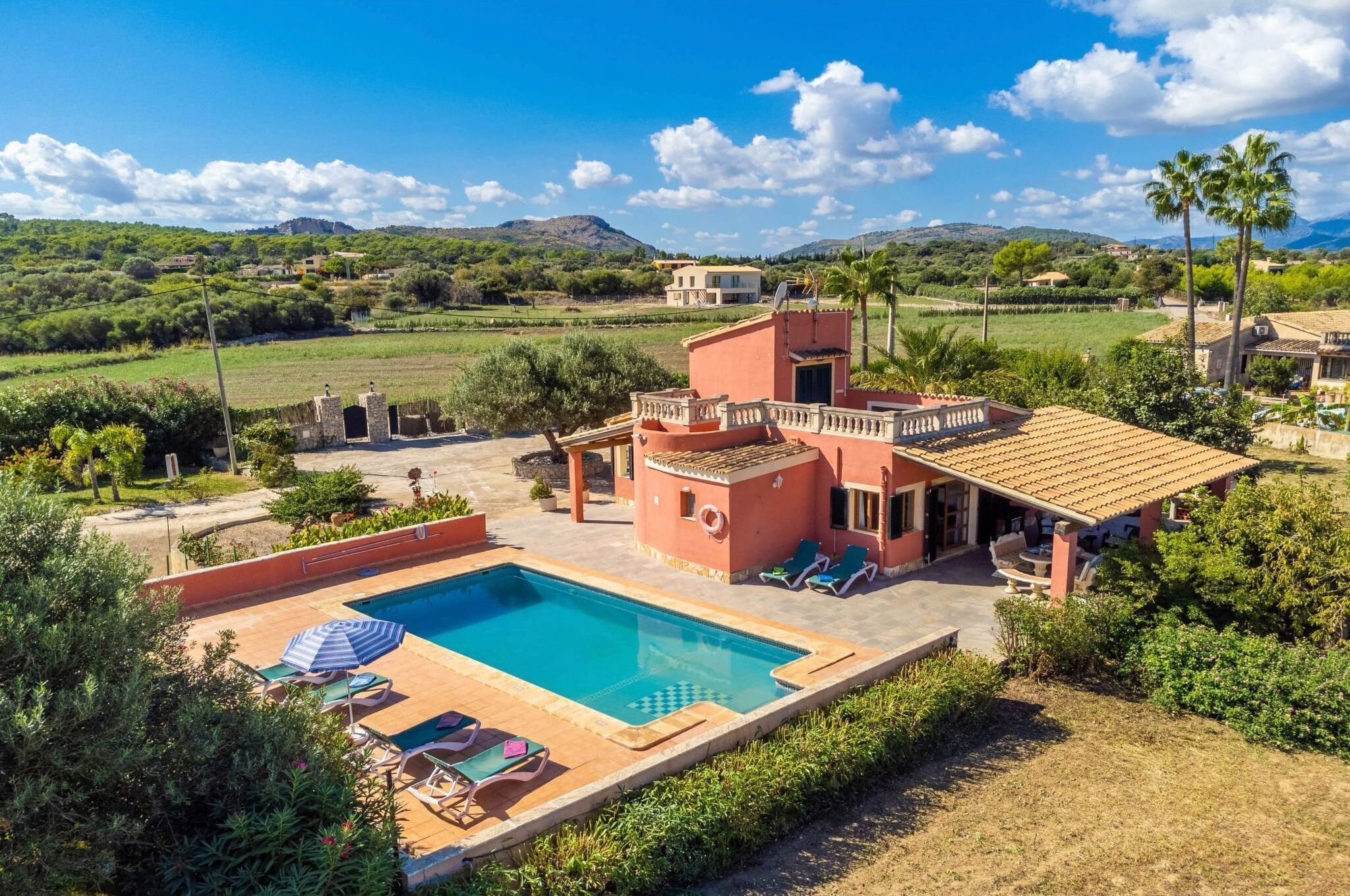 Eine Villa mit Swimmingpool, Sitzgelegenheiten im Freien und Blick auf die Landschaft.