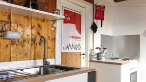 A kitchen with wooden paneling, a stainless steel sink, a stove, and a refrigerator.