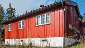 A red wooden house with white trim, a chimney, and a satellite dish.
