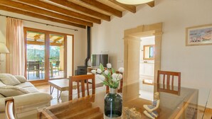Amplia sala de estar con techo de madera, una mesa de comedor con sillas, un sofá y un televisor.