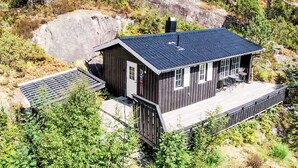 Eine Holzhütte mit dunklem Dach, einem Schornstein und einer Terrassenfläche mit Sitzgelegenheiten.