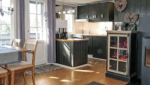 Eine moderne Küche mit Holzboden, einem Essbereich mit Tisch und Stühlen sowie einer integrierten Kochinsel mit Spüle.