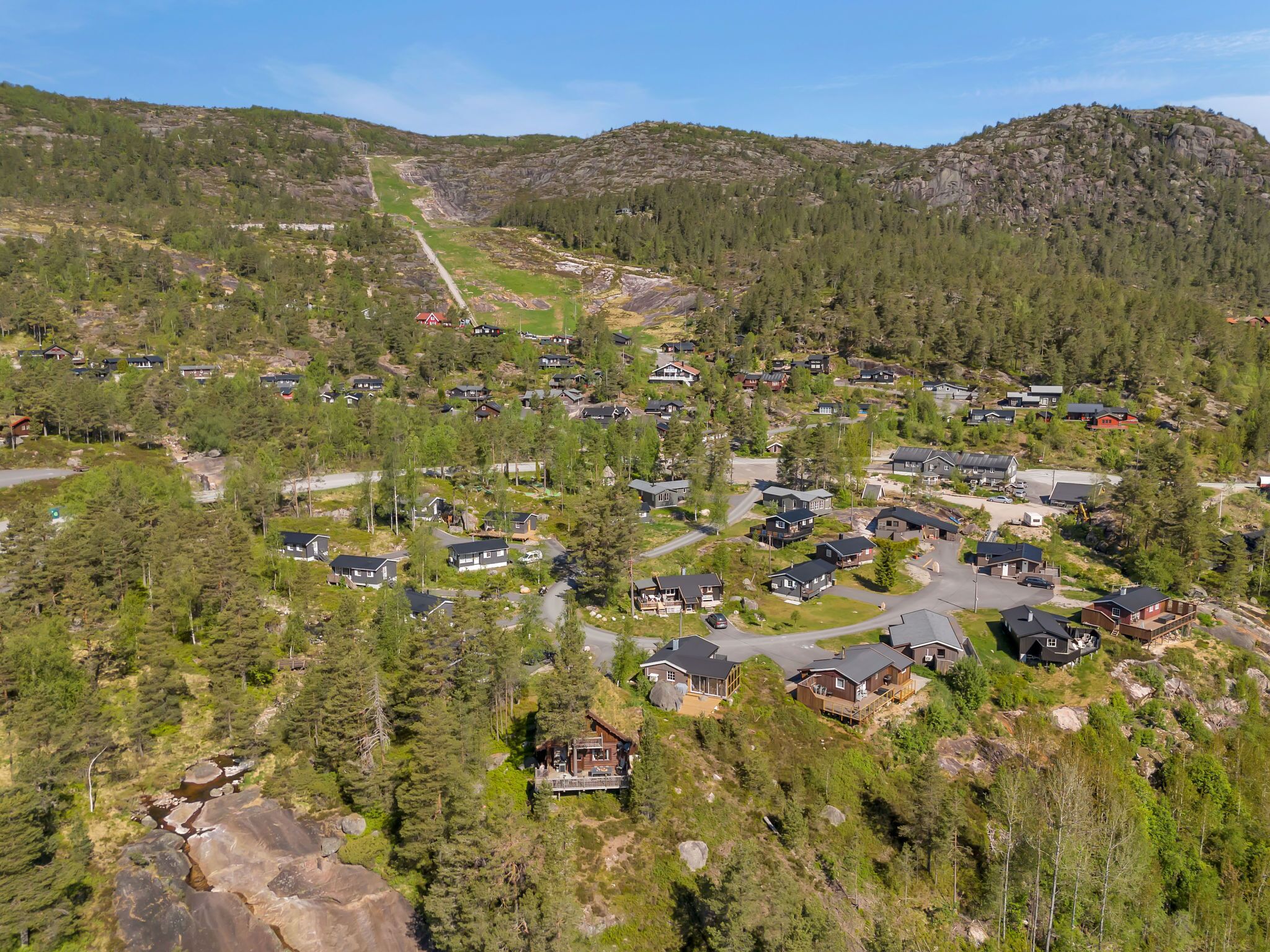 A residential area with houses surrounded by dense forest and hills.