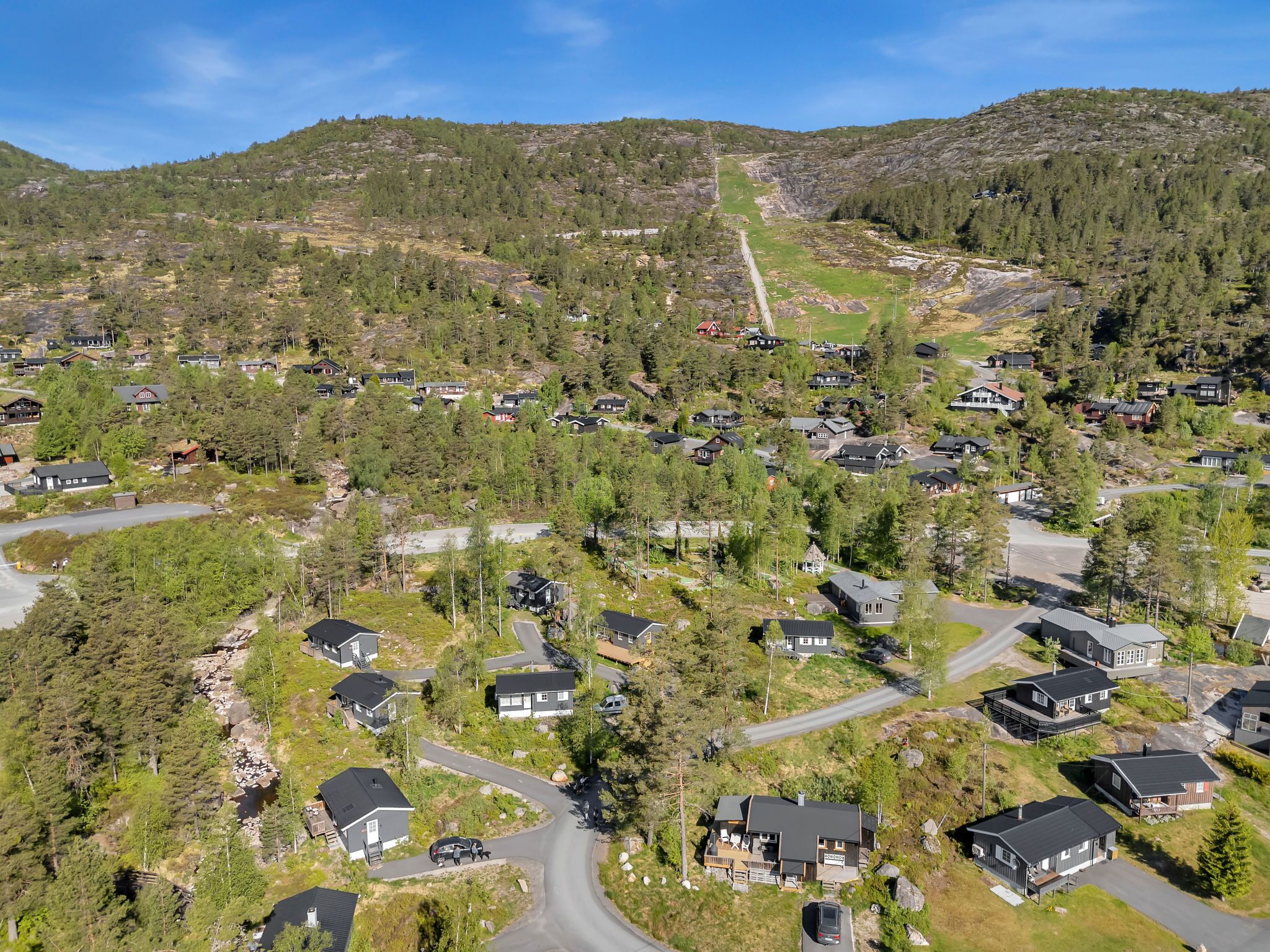 A residential area with houses surrounded by trees and hills.
