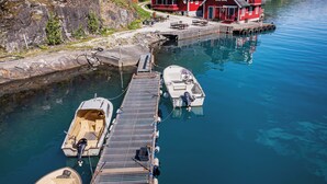 A harbor with boats docked, a pier, and a red building with a balcony. - Vardeheii by Interhome (Arnafjord)