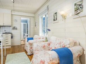 Ein Zimmer mit zwei blumengemusterten Betten, einer kleinen Küchenzeile, einer Uhr und einem Fenster mit Blick.
