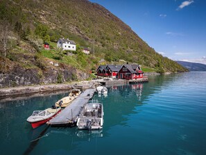 A coastal scene with a dock, boats, and houses by the water.