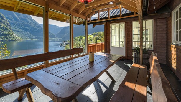 Una terraza de madera con un banco que da a un lago y montañas.