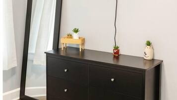 A dark wooden dresser with drawers, a flat-screen TV mounted above it, and two small potted plants on the dresser.
