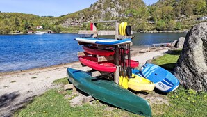 Een oeverlandschap met een rij kajaks en paddleboards op een houten rek.