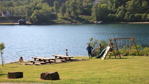 Een park aan het meer met picknicktafels, een schommel en een speeltuin.