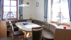 Een gezellig eetgedeelte met een ronde tafel, comfortabele zitplaatsen en een blauwe decoratieve schaal.