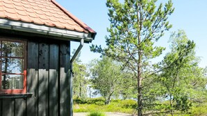 Une cabane en bois avec un toit recouvert de tuiles rouges et une fenêtre dotée d’un cadre rouge.