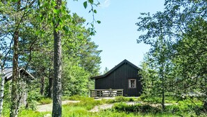 Un chalet rustique, entouré d’une végétation luxuriante et d’arbres.