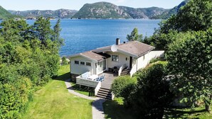 Une maison avec une terrasse, une antenne parabolique et une vue sur un lac et des montagnes.