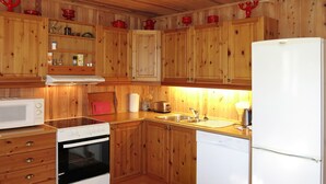 Une cuisine équipée de meubles en bois, d’un four à micro-ondes, d’un four traditionnel, d’un évier et d’un réfrigérateur.