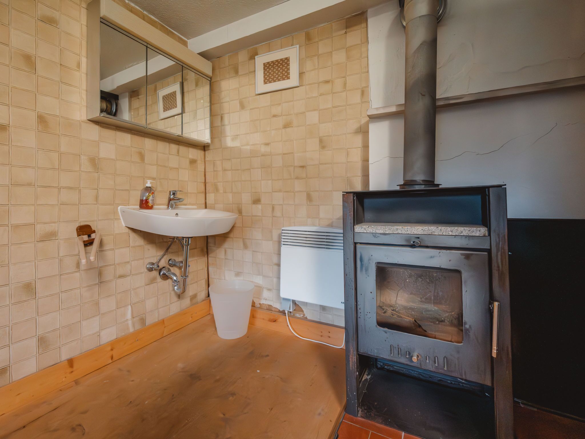 Ein Badezimmer mit Waschbecken, Spiegel und einem Kaminofen.